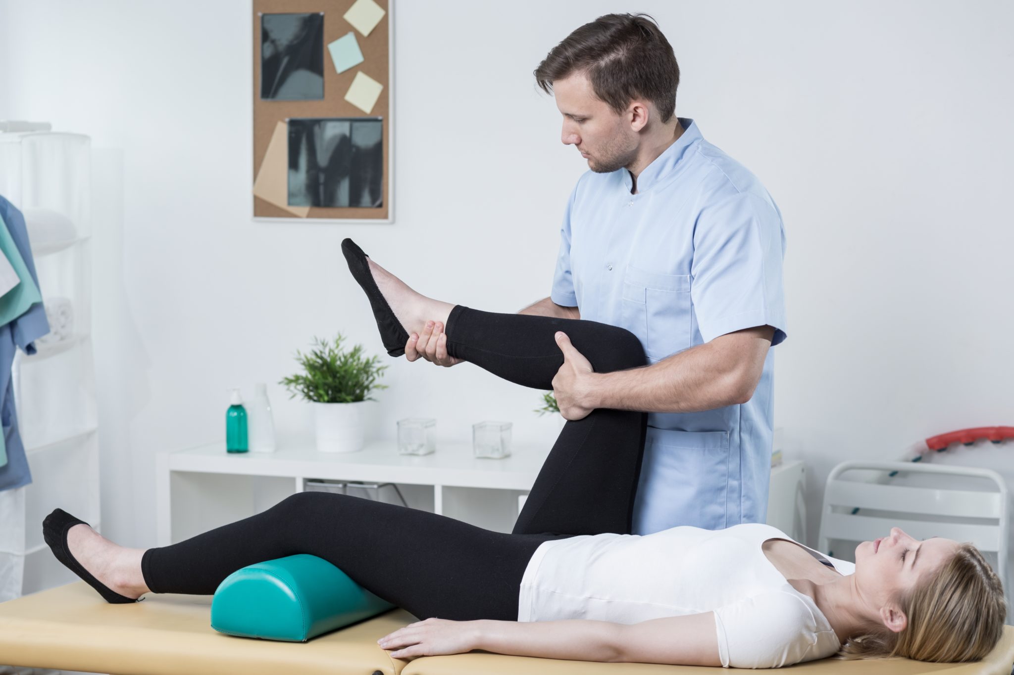 Male physiotherapist exercising with patient having knee pain